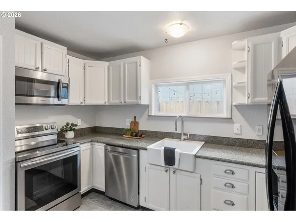 a kitchen with stainless steel appliances granite countertop a sink a stove a microwave a refrigerator and cabinets