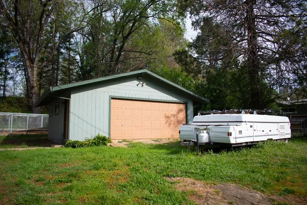 a view of backyard with barbeque and large trees