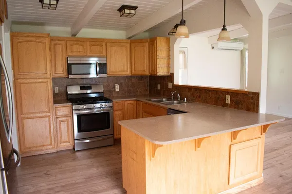 a kitchen with stainless steel appliances granite countertop a refrigerator a stove top oven a sink a dining table and chairs with wooden floor