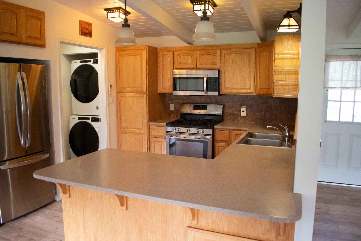 4881 Marshall Road Garden Valley, CA 95633 - Photo 9 of 25 a kitchen with stainless steel appliances granite countertop a refrigerator a stove top oven a sink a dining table and chairs with wooden floor