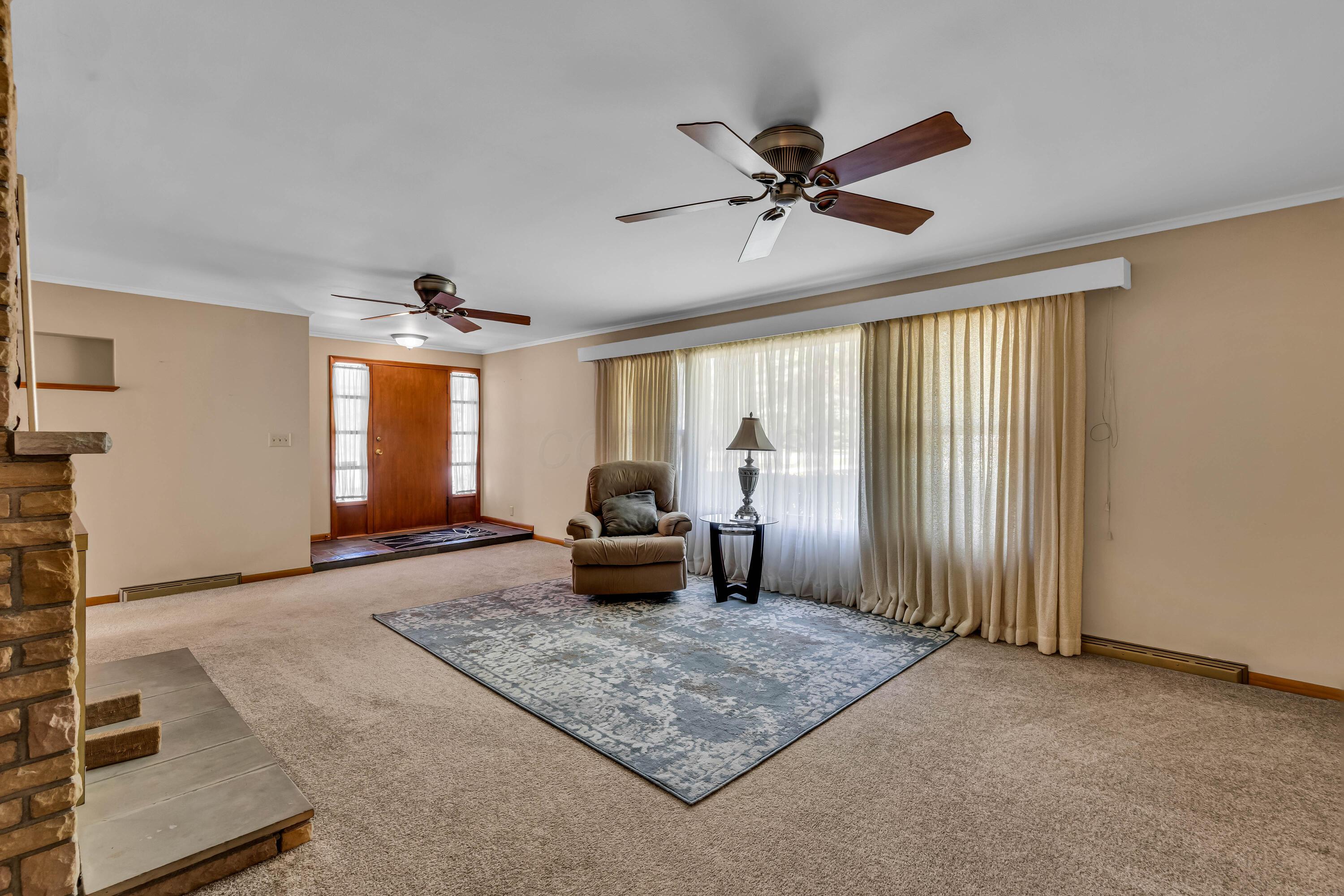 1213 East Cooke Road Columbus, OH 43224 - Photo 14 of 57 • Light sand carpet • Hardwood flooring under carpet • Tan painted walls • (2) ceiling fans • Stone fireplace with raised hearth • Crown molding