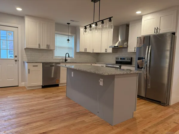 a kitchen with stainless steel appliances granite countertop a sink a stove top oven a refrigerator with island and chairs