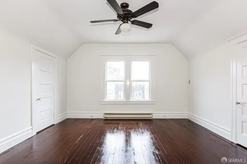 an empty room with wooden floor fan and windows