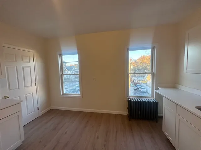 a view of an empty room with a window and wooden floor