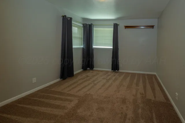a view of an empty room and chandelier fan