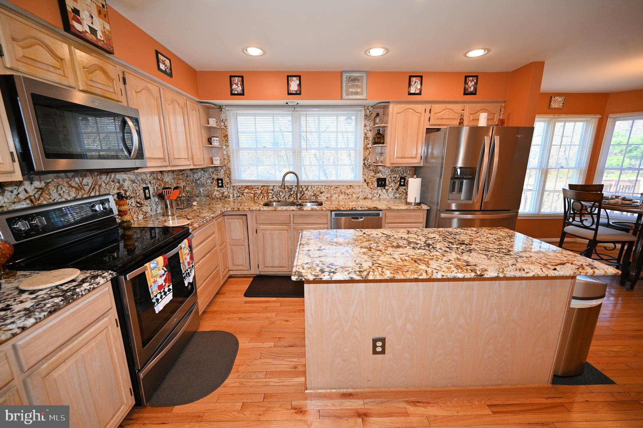 7729 Castle Rock Drive Clinton, MD 20735 - Photo 5 of 65 a kitchen with kitchen island granite countertop wooden cabinets and a stove top oven with wooden floor