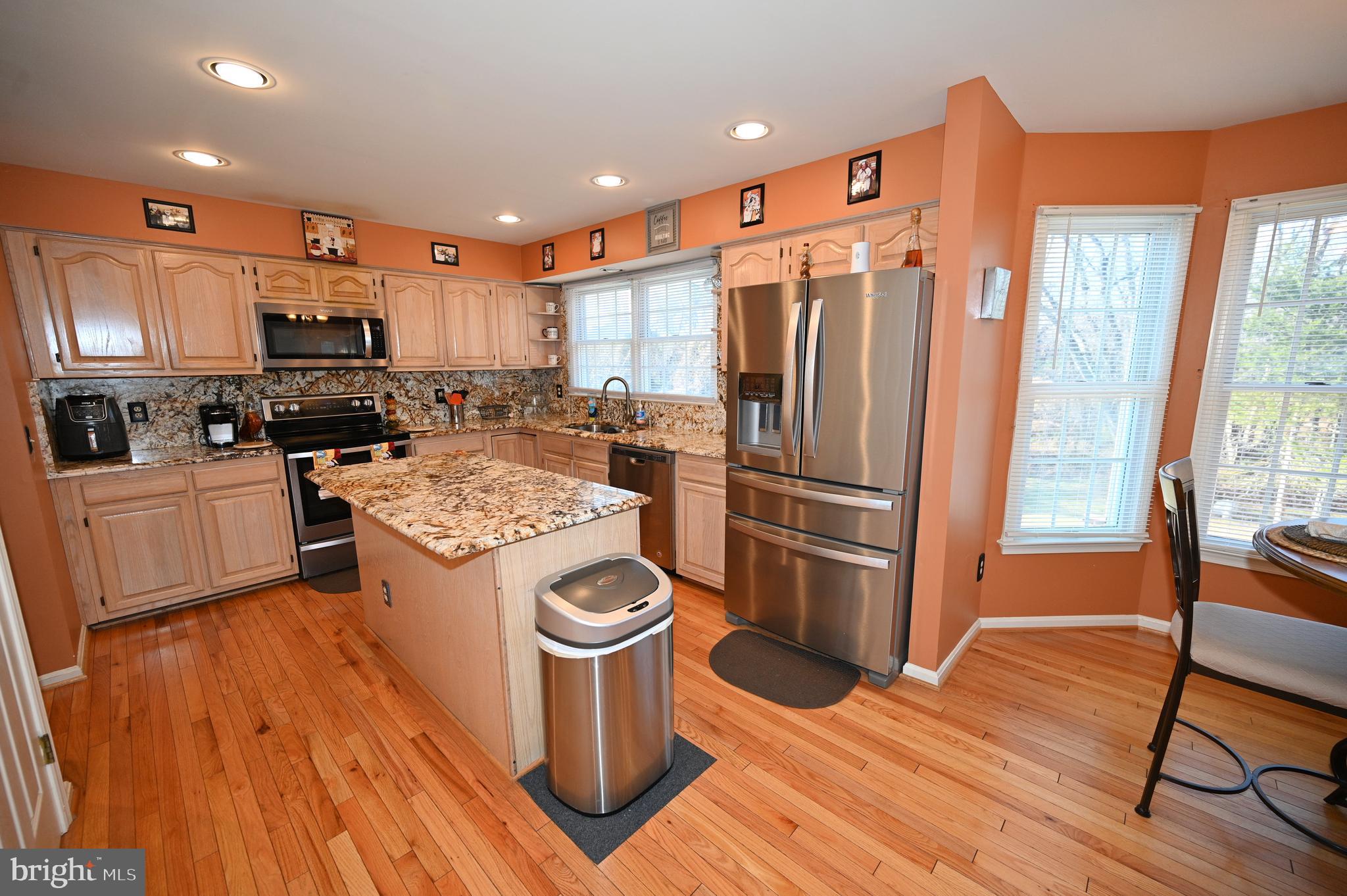7729 Castle Rock Drive Clinton, MD 20735 - Photo 10 of 65 a kitchen with stainless steel appliances a stove a refrigerator a sink a dining table and chairs with wooden floor