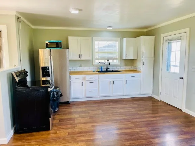a kitchen with stainless steel appliances a refrigerator sink and wooden floor