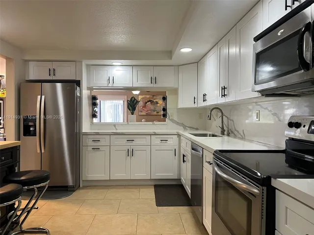 a kitchen with white cabinets stainless steel appliances and sink