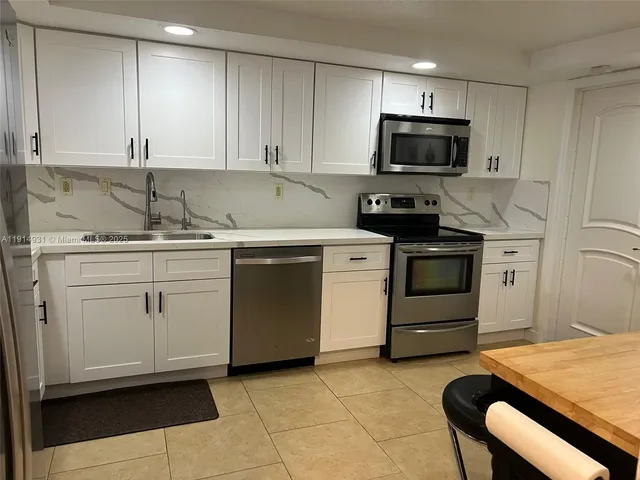 a kitchen with stainless steel appliances a stove a microwave and white cabinets