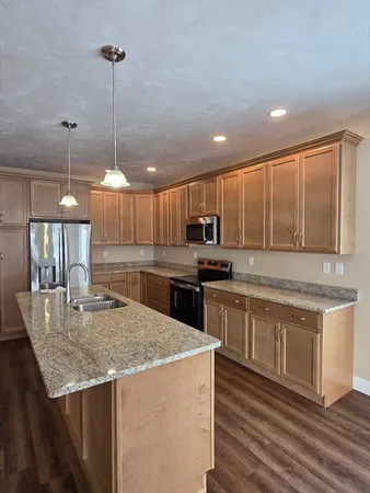 a kitchen with stainless steel appliances granite countertop a sink a stove and a wooden floors