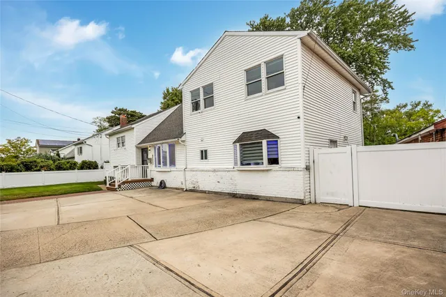 a view of a white house with a yard and large tree