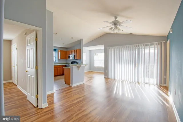a view of a hallway with wooden floor and a kitchen