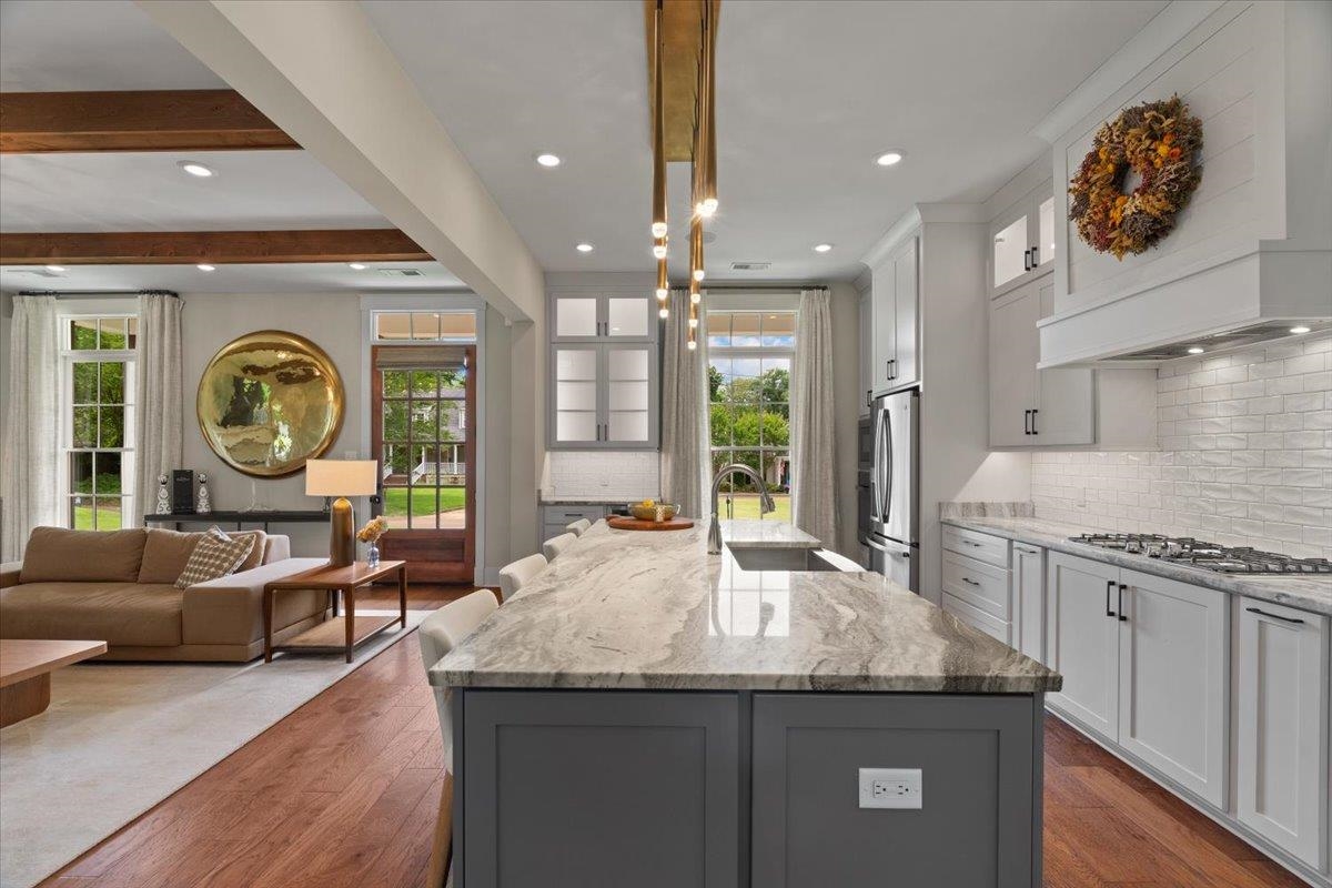 240 Burrows Road Collierville, TN 38017 - Photo 4 of 37 Open-concept kitchen featuring an oversized island with an undermount sink, gas range, light gray cabinetry, and white subway tile backsplash