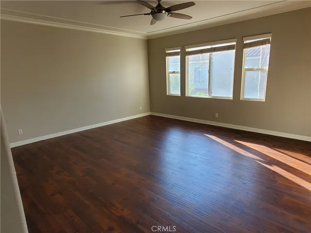 an empty room with wooden floor fan and windows