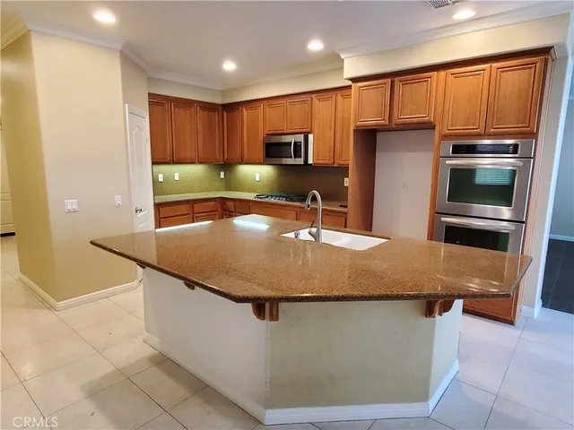 a kitchen with stainless steel appliances granite countertop a sink a microwave a refrigerator and a stove