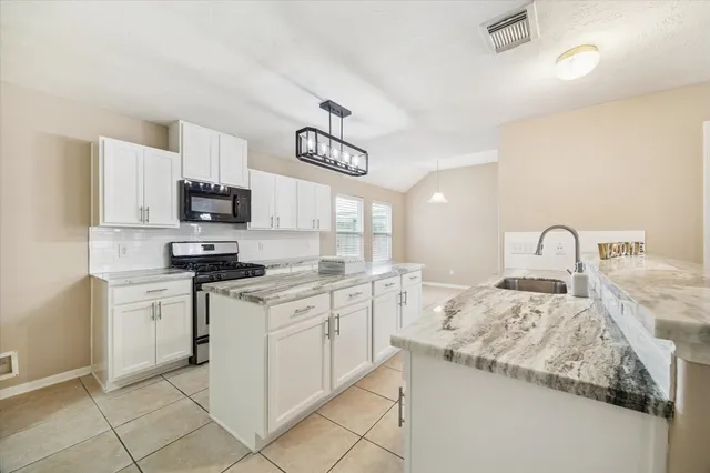 a kitchen with granite countertop a sink stainless steel appliances and white cabinets