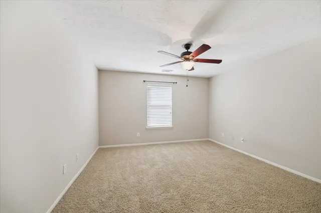 an empty room with a window and a ceiling fan