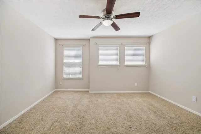 an empty room with a window and a fan