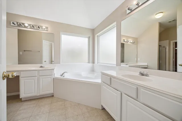 a bathroom with a sink double vanity mirror and a bathtub