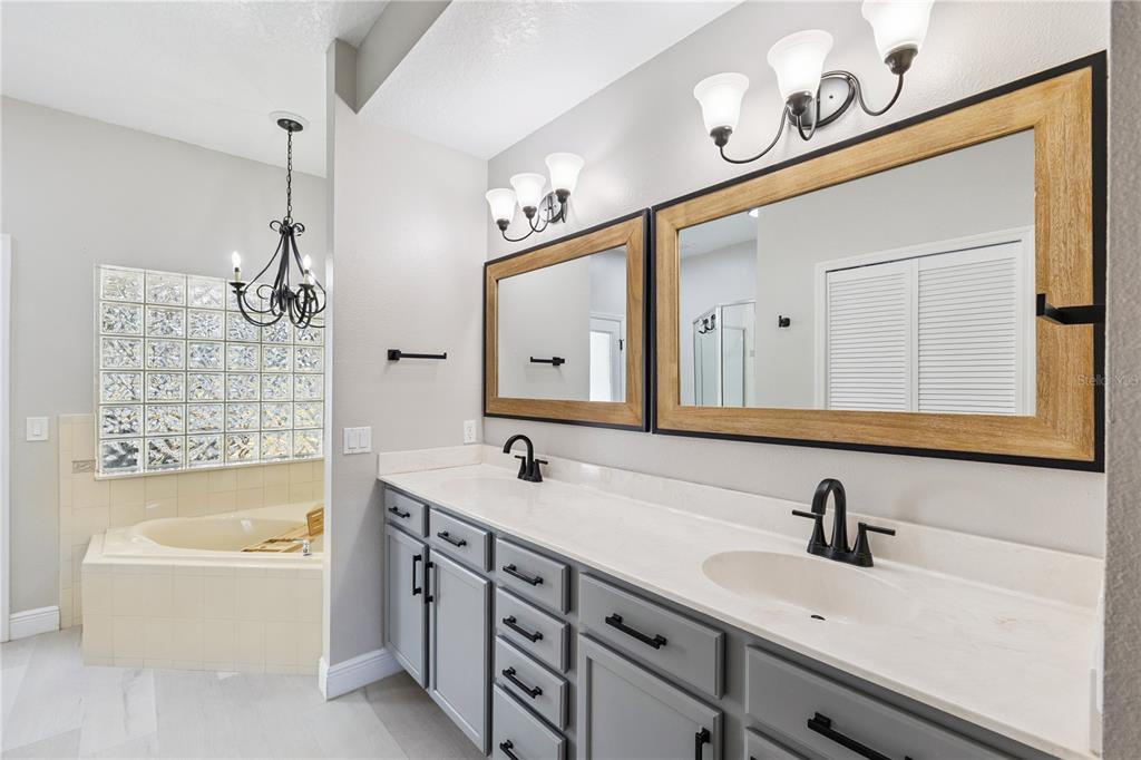 609 Rhodes Drive DeLand, FL 32720 - Photo 16 of 32 a bathroom with a tub a sink double vanity and mirror