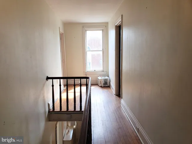 a view of a hallway with wooden floor and staircase