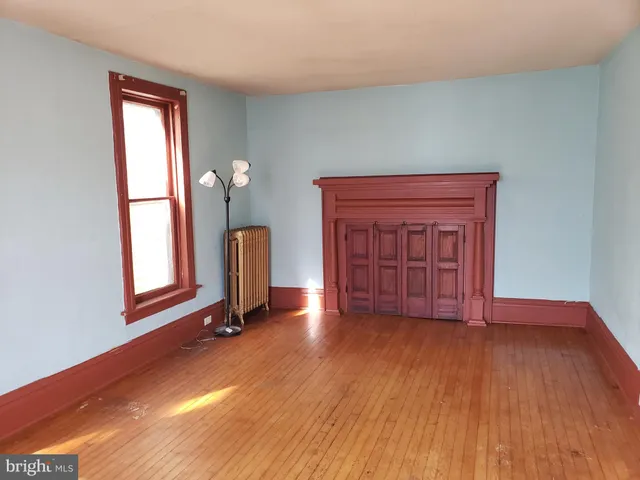 a view of an empty room with window and wooden floor