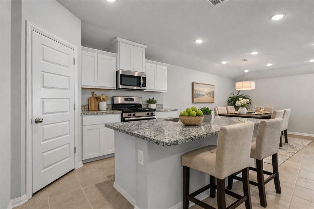 1504 Foxglove Van Alstyne, TX 75495 - Photo 3 of 12 a kitchen with stainless steel appliances granite countertop a kitchen island a stove a table and chairs