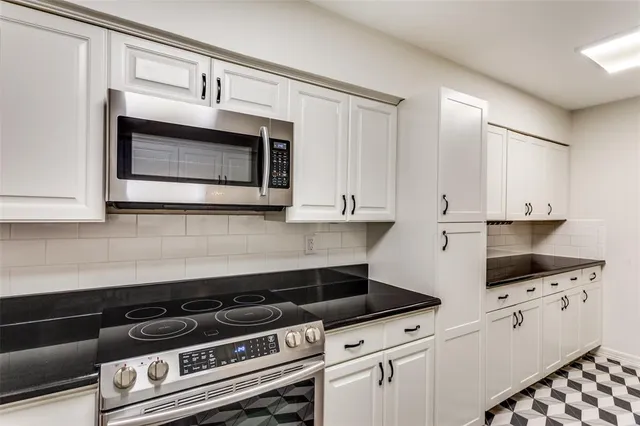 a kitchen with granite countertop white cabinets and appliances