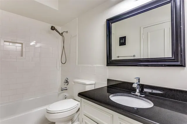 a bathroom with a granite countertop sink a toilet and a mirror