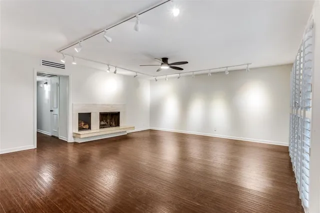 an empty room with wooden floor fireplace and windows