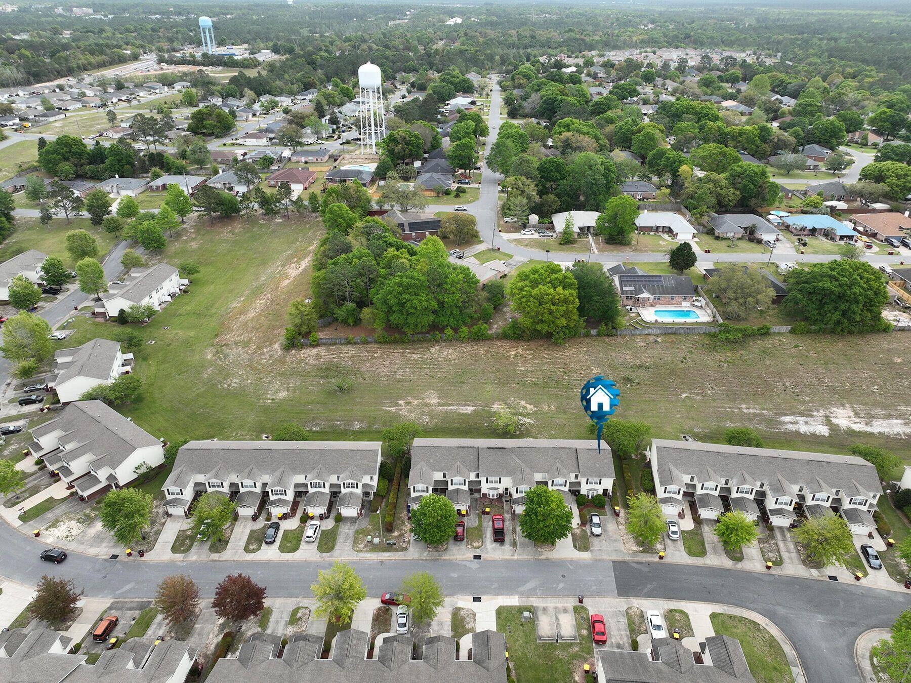 an aerial view of ocean and residential houses with outdoor space