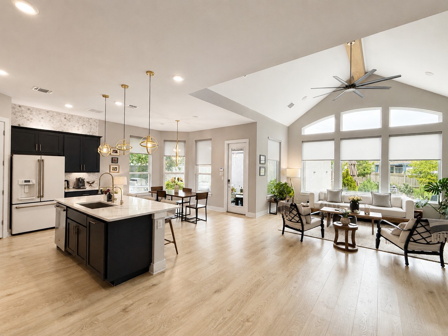 Bright open-concept living space with soaring ceilings, large windows, and a modern kitchen.