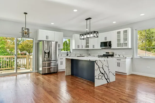 a kitchen with stainless steel appliances a stove a sink a refrigerator a center island and wooden floor