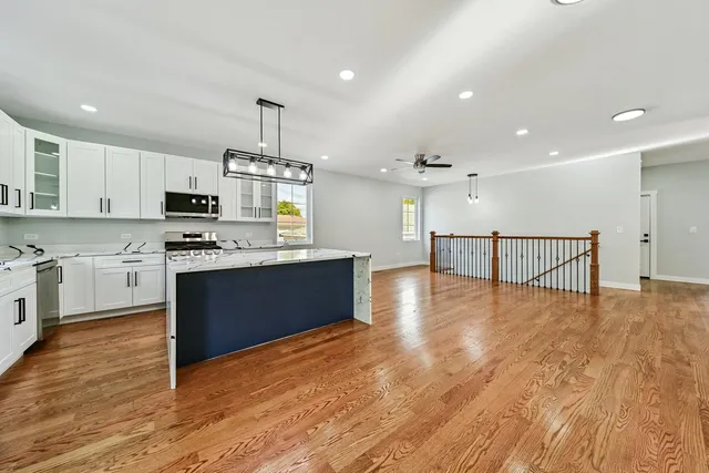 a large kitchen with stainless steel appliances granite countertop a stove top oven a sink dishwasher and white cabinets with wooden floor