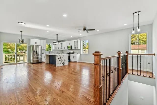 a open kitchen with stainless steel appliances granite countertop a stove kitchen island a refrigerator and a table with wooden floor