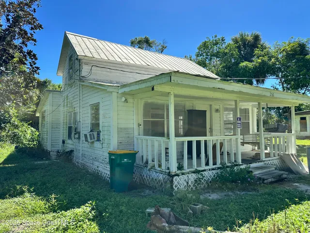 a view of a house with brick walls and a yard with plants