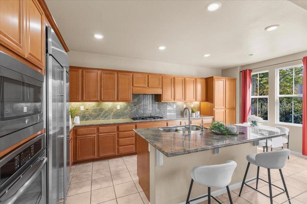 838 Luminara Way San Marcos, CA 92078 - Photo 28 of 54 a kitchen with stainless steel appliances granite countertop wooden cabinets a stove top oven a sink and dishwasher