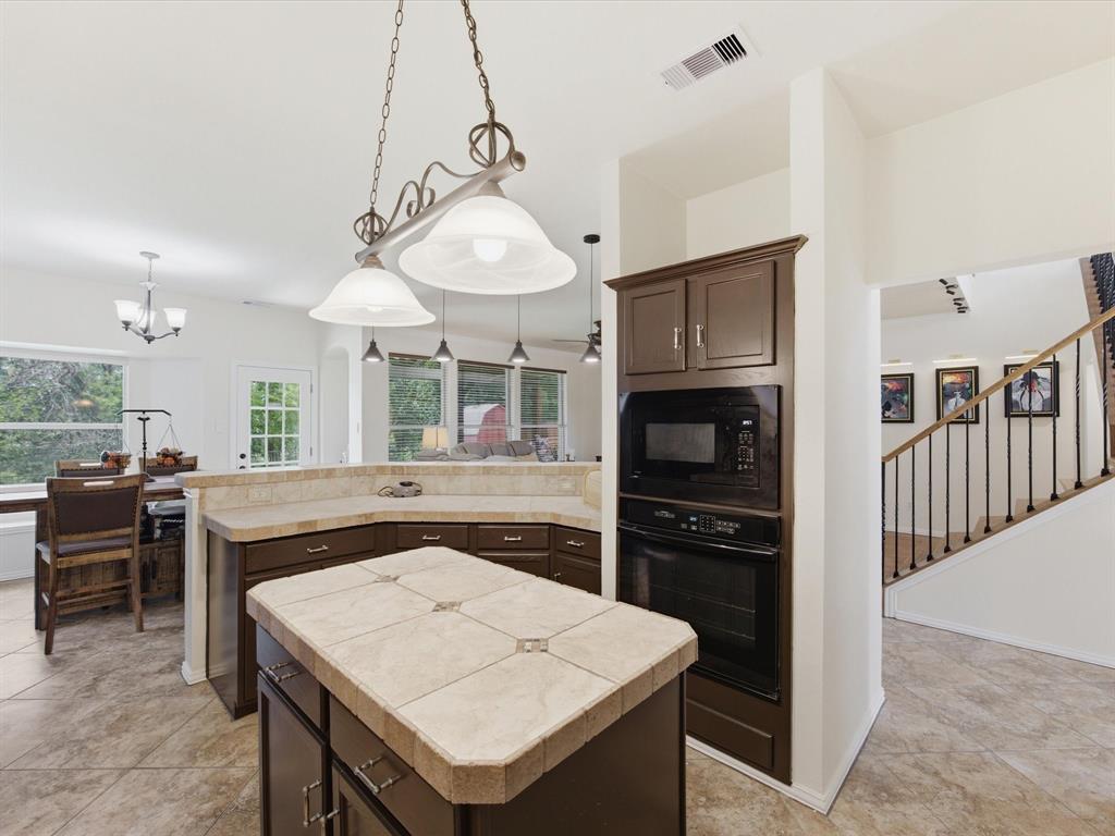 4008 Falcon Ridge Drive Haltom City, TX 76137 - Photo 11 of 40 Kitchen featuring a tile-topped island, dark wood-finish cabinetry, and built-in black appliances