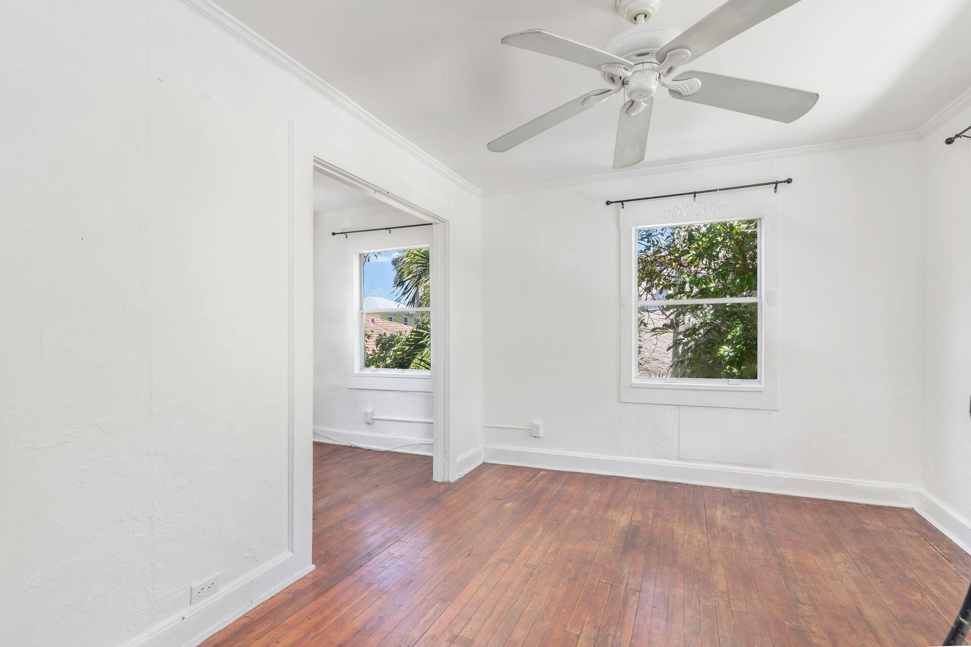 214 Conniston Road West Palm Beach, FL 33405 - Photo 4 of 18 an empty room with wooden floor chandelier fan and windows