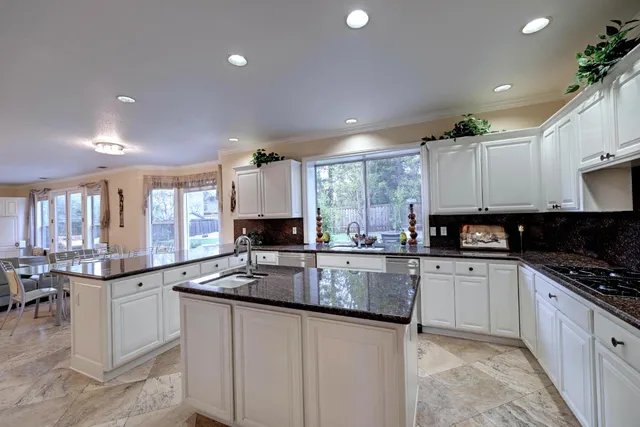 a kitchen with kitchen island granite countertop a sink counter top space appliances and cabinets