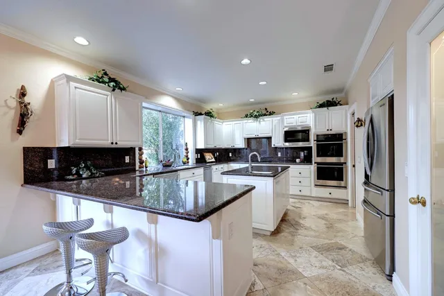 a large kitchen with stainless steel appliances granite countertop a stove refrigerator and cabinets