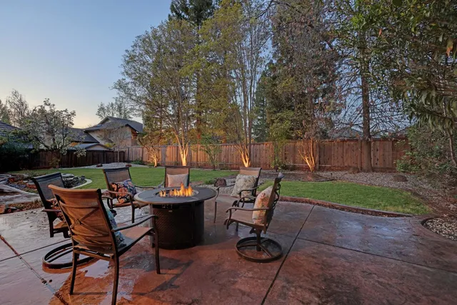 a view of a park with large trees and wooden fence