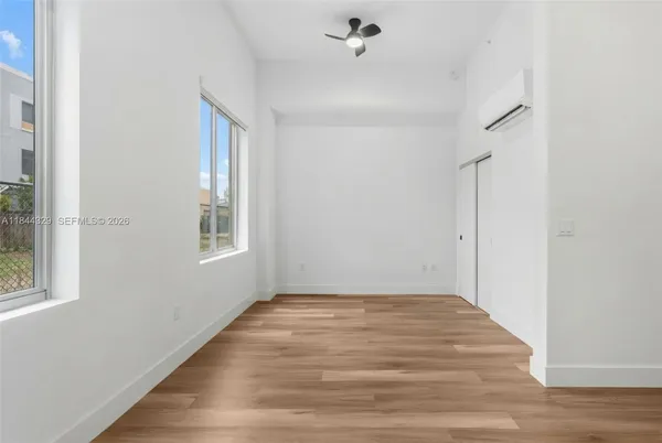 a view of empty room with wooden floor and fan