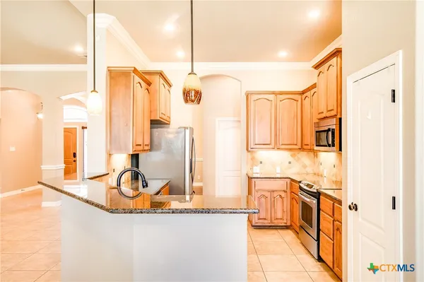 a kitchen with stainless steel appliances granite countertop a sink a stove and a refrigerator
