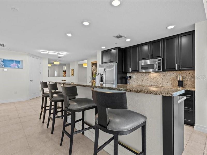 331 Cleveland Street, Unit 806 Clearwater, FL 33755 - Photo 25 of 83 a kitchen with granite countertop a table chairs microwave and cabinets