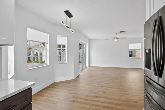 an empty room with wooden floor chandelier fan and windows