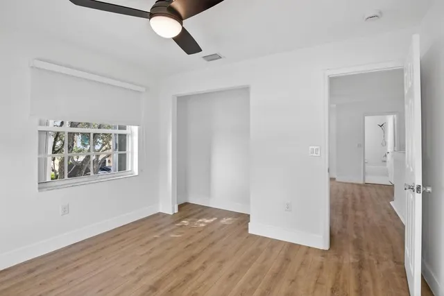 a view of empty room with wooden floor and fan