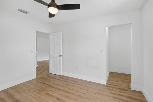 an empty room with wooden floor and a ceiling fan