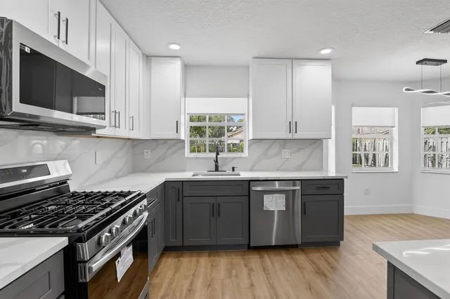 a kitchen with stainless steel appliances granite countertop a sink stove and cabinets